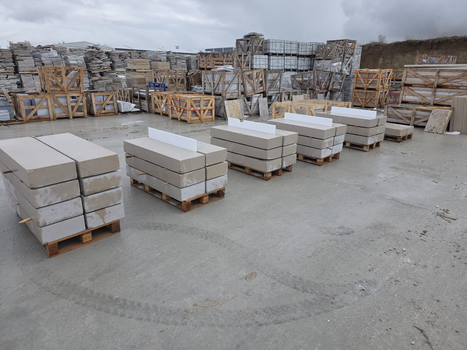 Pallets of cut stone step treads in a stone yard, with crated stone products stacked behind